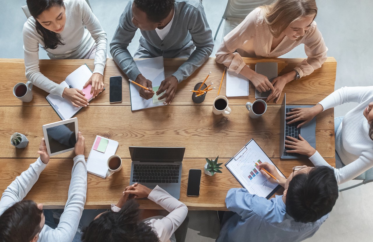 Office lifestyle concept. Top view of international young business team having meeting at office, sitting around table